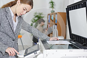 Beautiful girl operating copier in modern office