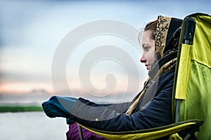 Beautiful girl outdoors on a fishing chair looking away