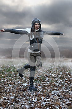 Beautiful girl with outstretched arms running in a field