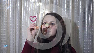 Beautiful girl paints a heart on glass