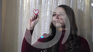 Beautiful girl paints a heart on glass