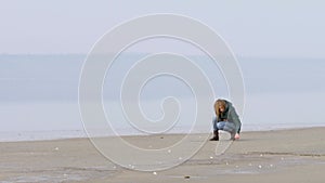 Beautiful girl paints the words and wrote in the sand on the beach.