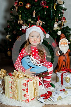 Beautiful girl in pajamas with blue skate is waiting Christmas and New year