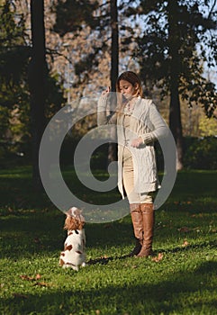 Beautiful girl in the park doing obedience excersize with her dog Cavalier King Charles Spaniel