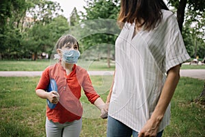 Beautiful girl in the park wearing medical mask and looking at her mom