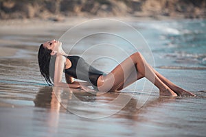 Beautiful girl with a perfect body lying on the beach, by the sea.