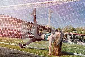 A beautiful girl with a perfect figure stands near a football goal at the stadium.  Fitness and healthy lifestyle concept