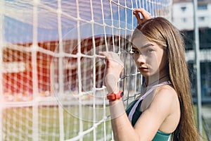 A beautiful girl with a perfect figure stands near a football goal at the stadium.  Fitness and healthy lifestyle concept