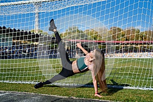 A beautiful girl with a perfect figure stands near a football goal at the stadium.  Fitness and healthy lifestyle concept