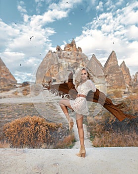 Beautiful girl with perfect legs posing in Cappadocia mountain canyon in a fringed jacket