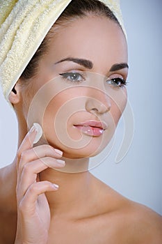 Beautiful girl with perfect skin applying cosmetics to her face