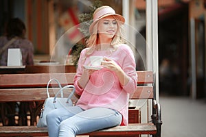 Beautiful girl in a pink dress sitting in a cafe with a tablet and a Cup of cappuccino. Young happy woman using tablet