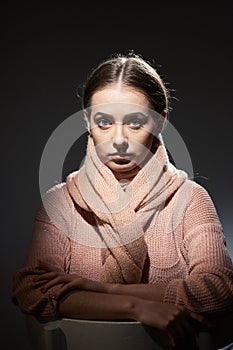 Beautiful girl in pink knitted sweater. emotional portrait on a dark background.