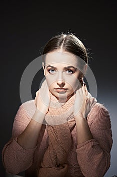 Beautiful girl in pink knitted sweater. emotional portrait on a dark background.