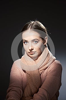 Beautiful girl in pink knitted sweater. emotional portrait on a dark background.