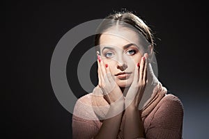 Beautiful girl in pink knitted sweater. emotional portrait on a dark background.