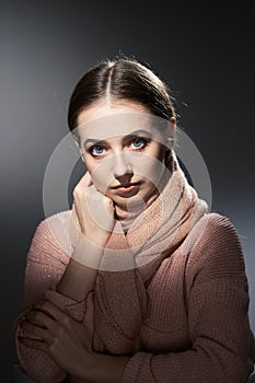 Beautiful girl in pink knitted sweater. emotional portrait on a dark background.