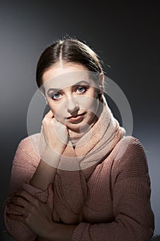 Beautiful girl in pink knitted sweater. emotional portrait on a dark background.