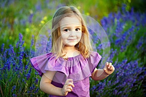 Beautiful girl playing in blooming lavender flower field. Children play in spring flowers.