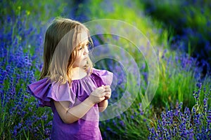 Beautiful girl playing in blooming lavender flower field. Children play in spring flowers.