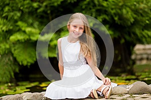 Beautiful girl playing on nature background. Smiling child looks in camera in summer park outdoor on a sunny day