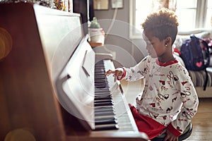 Beautiful girl is playing on piano x-mas music. Concept Christmas, New Year, holiday, family happiness, childhood