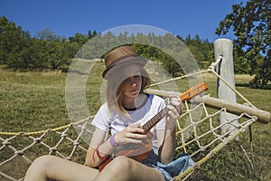 Beautiful girl playing ukulele - hawaiian guitar in hammock