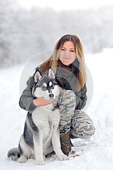 The beautiful girl plays with a puppy huskies