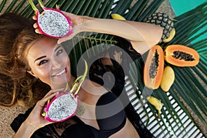Beautiful girl in pool at hotel. Black swimsuit near tropical fruit papaya ,dragonfruit, pineapple, banana, summer vacation,