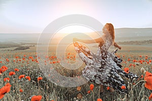 beautiful girl in a poppy field at sunset.