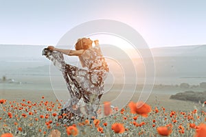 beautiful girl in a poppy field at sunset.