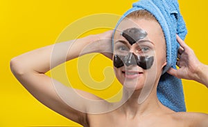 Beautiful girl poses for the camera with a black face mask on a yellow background
