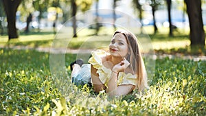 A beautiful girl poses lying on the grass in the park.