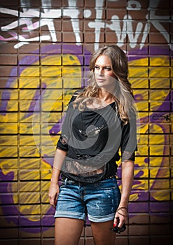 Young woman with black blouse and long hair against a graffiti wall