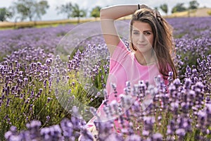 Beautiful girl is posing with hand in in her long hair in lavender field