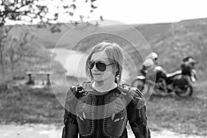 Beautiful girl posing on a motorcycle background. Dressed in a turtle jacket, body armor. Nature and travel is an extreme hobby.