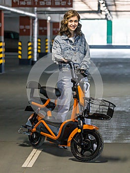 beautiful girl posing sitting on an electric scooter in the parking lot photo