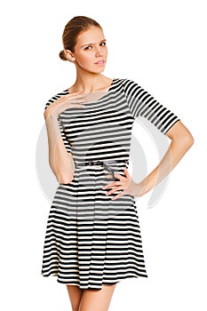 Beautiful girl posing in striped white dress with hand on hip against white background