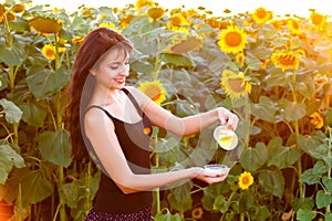 Beautiful girl pours sunflower oil from the pitcher