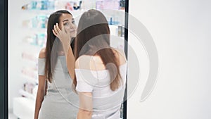 Beautiful girl preens herself in front of mirror in cosmetic store, slow motion