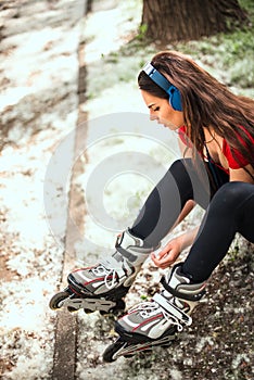 Beautiful girl is prepairing for rollerblading at the street