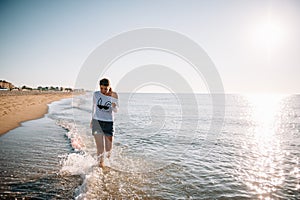 Beautiful girl with pretty legs walking along the seashore in the summer hot day near the sea