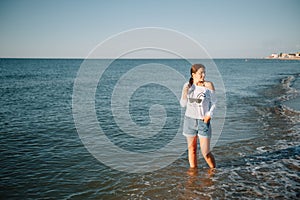 Beautiful girl with pretty legs walking along the seashore in the summer hot day near the sea