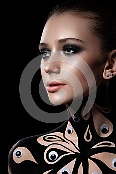 Beautiful girl with a professional evening make-up. neck and shoulders are painted with black paint