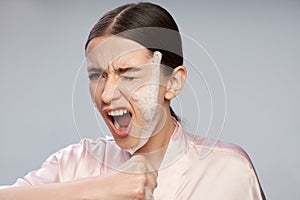 Beautiful girl with purifying foam on face screaming