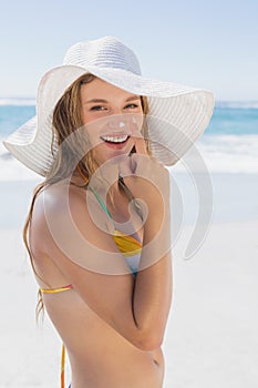 Beautiful girl putting spf on nose on the beach smiling at camera