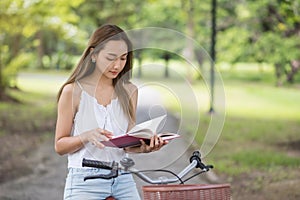 Beautiful girl read book and sit on bicycle