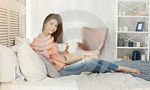 Beautiful girl reading book in bed at home