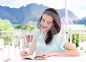 Beautiful girl reading book outside on table