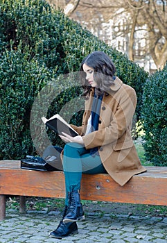 Beautiful girl reading book in the park in spring